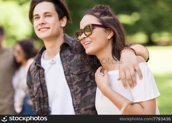 people and leisure concept - happy couple with friends at summer park. happy couple with friends at summer park