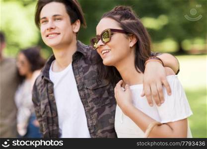 people and leisure concept - happy couple with friends at summer park. happy couple with friends at summer park