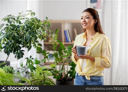 people and leisure concept - happy smiling asian woman drinking coffee at home. happy smiling asian woman drinking coffee at home