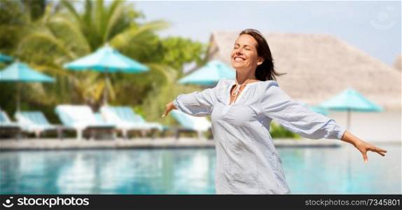 people and leisure concept - happy smiling woman enjoying sun over swimming pool of touristic resort background. happy woman over swimming pool of touristic resort
