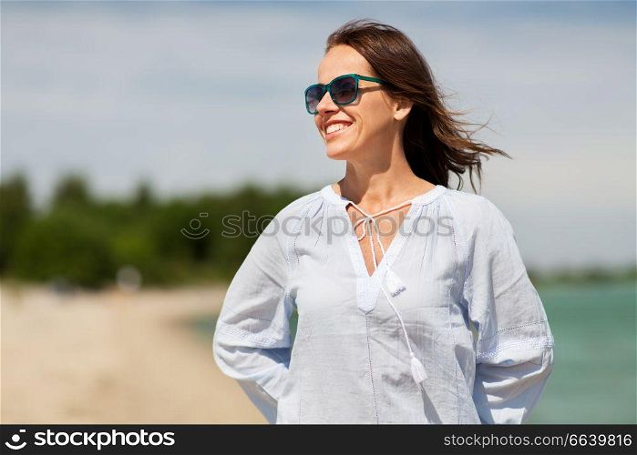 people and leisure concept - happy smiling woman in sunglasses on summer beach. happy smiling woman in sunglasses on summer beach