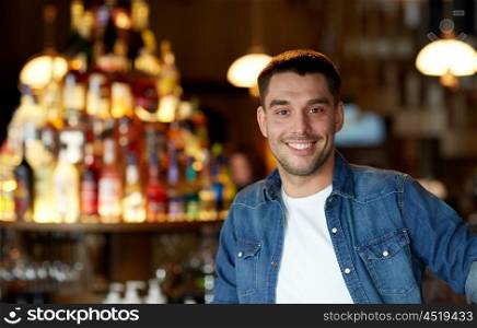 people and leisure concept - happy smiling young man at bar or pub. happy smiling young man at bar or pub