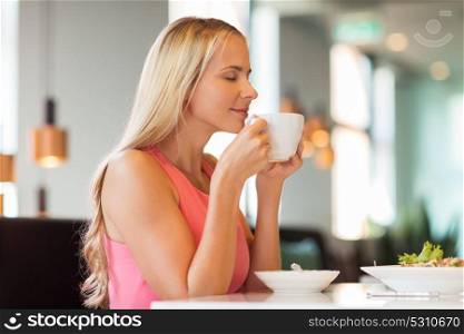 people and leisure concept - happy woman drinking coffee and eating at restaurant. woman eating and drinking coffee at restaurant