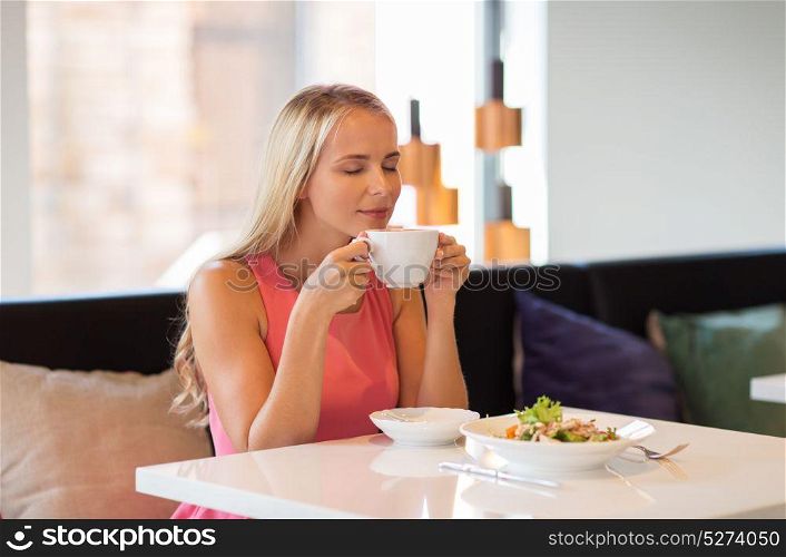 people and leisure concept - happy woman drinking coffee and eating salad for lunch at restaurant. woman eating and drinking coffee at restaurant
