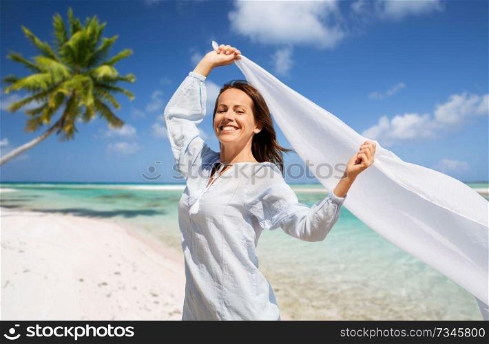 people and leisure concept - happy woman with shawl waving in wind over tropical beach background in french polynesia. happy woman with shawl waving in wind on beach