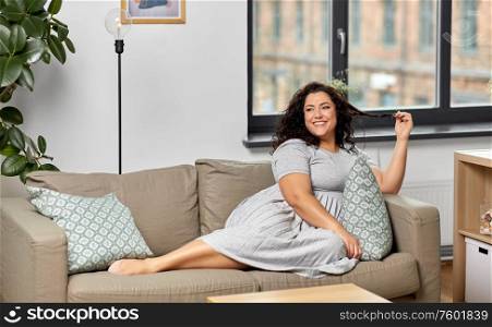 people and leisure concept - happy young woman lying on sofa at home. happy young woman lying on sofa at home