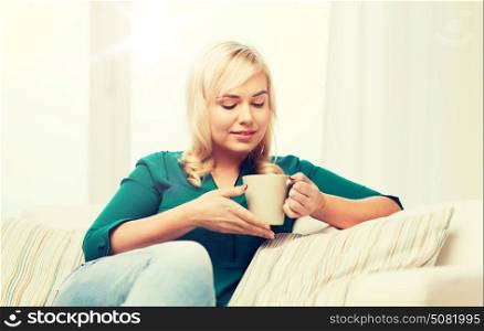 people and leisure concept - happy young woman sitting on sofa at home. happy young woman at home
