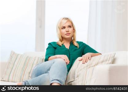 people and leisure concept - happy young woman sitting on sofa at home. happy young woman at home