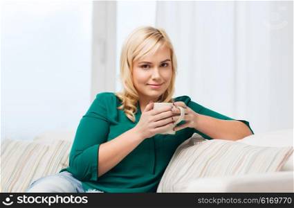 people and leisure concept - happy young woman with cup of tea or coffee at home. happy woman with cup of tea or coffee at home