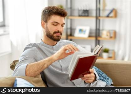 people and leisure concept - man reading book at home. man reading book at home