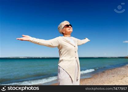 people and leisure concept - portrait of happy senior woman in sunglasses on beach in estonia. portrait of senior woman in sunglasses on beach