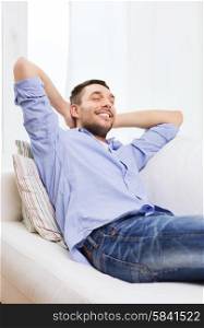 people and leisure concept - smiling man with closed eyes relaxing on couch at home