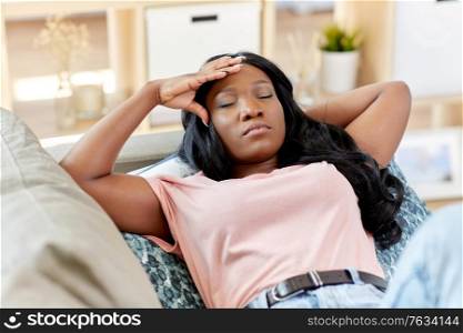 people and leisure concept - tired african american woman lying on sofa at home. tired african american woman lying on sofa at home