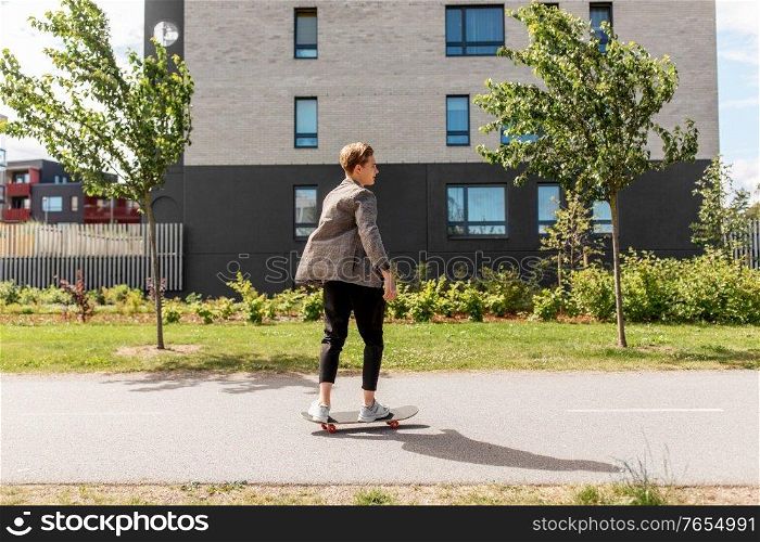 people and leisure concept - young man or teenage boy riding skateboard on city street. teenage boy on skateboard on city street