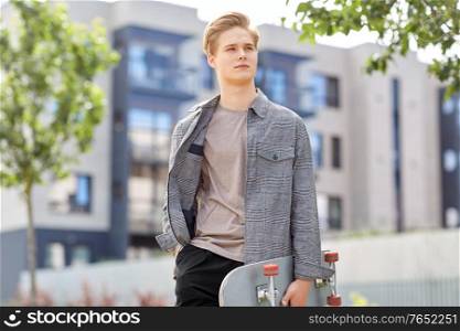people and leisure concept - young man or teenage boy with skateboard on city street. teenage boy with skateboard on city street