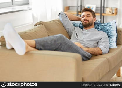 people and leisure concept - young man sitting on sofa at home. young man sitting on sofa at home