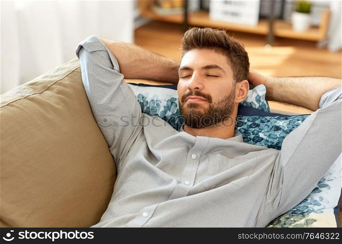 people and leisure concept - young man sleeping on sofa at home. young man sleeping on sofa at home