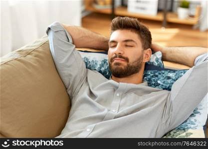 people and leisure concept - young man sleeping on sofa at home. young man sleeping on sofa at home