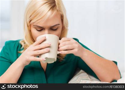 people and leisure concept - young woman drinking tea or coffee at home. happy woman with cup of tea or coffee at home