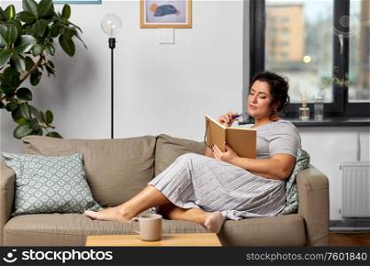 people and leisure concept - young woman with diary and pencil taking notes on sofa at home. young woman with diary on sofa at home