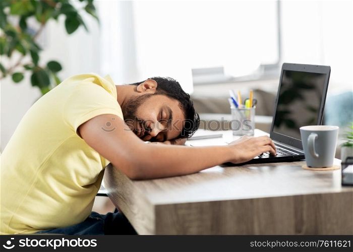people and lifestyle concept - tired indian man sleeping on table with laptop computer at home. indian man sleeping on table with laptop at home