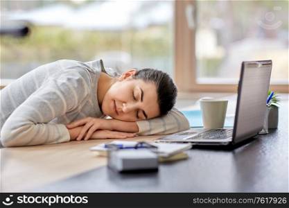 people and lifestyle concept - tired woman sleeping on table with laptop computer at home office. tired woman sleeping on table with laptop at home