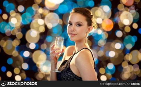 people and luxury concept - beautiful young asian smiling woman drinking non alcoholic champagne at party over holidays lights background. young asian woman drinking champagne at party