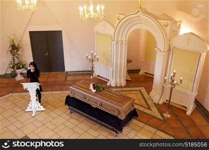 people and mourning concept - crying woman near coffin at funeral in christian orthodox church. crying woman near coffin at funeral in church