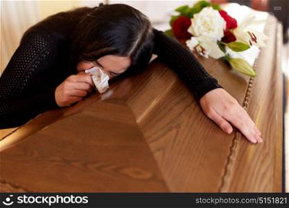 people and mourning concept - crying woman with coffin at funeral in church. woman with coffin crying at funeral in church