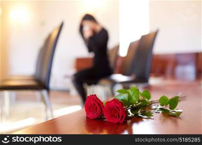 people and mourning concept - red roses and woman crying at funeral in church. red roses and woman crying at funeral in church