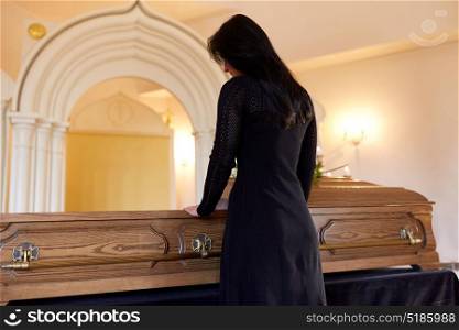 people and mourning concept - sad woman with coffin at funeral in orthodox church. sad woman with coffin at funeral in church