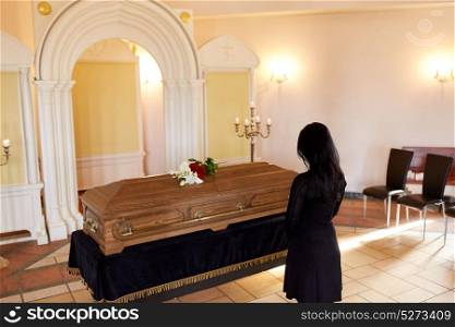 people and mourning concept - sad woman with coffin at funeral in orthodox church. sad woman with coffin at funeral in church