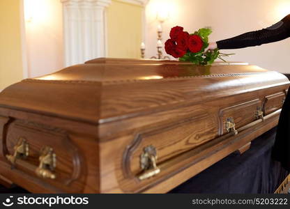 people and mourning concept - woman with red roses and coffin at funeral in church. woman with red roses and coffin at funeral