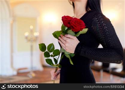 people and mourning concept - woman with red roses at funeral in church. woman with red roses at funeral in church