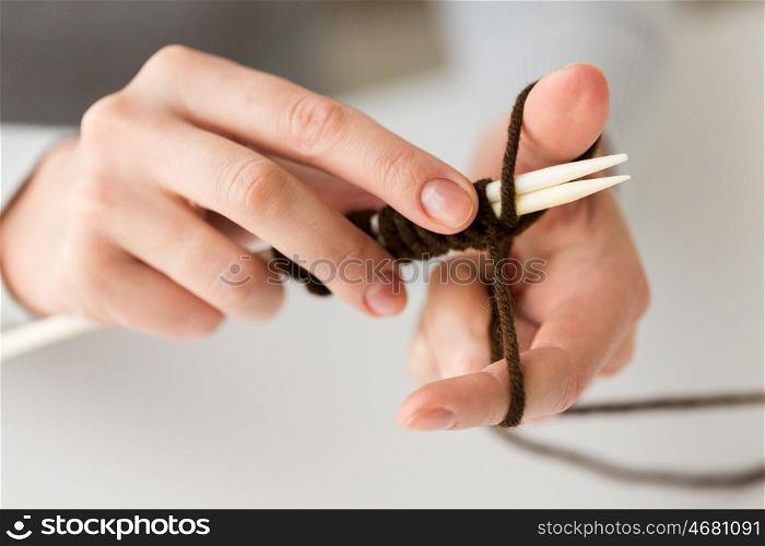 people and needlework concept - close up of woman hands knitting with needles and brown yarn. close up of hands knitting with needles and yarn