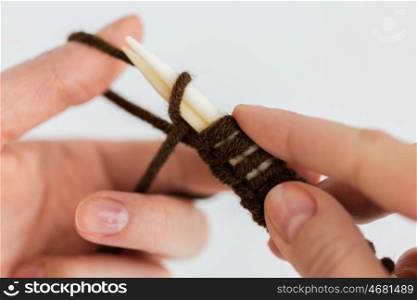 people and needlework concept - close up of woman hands knitting with needles and brown yarn. close up of hands knitting with needles and yarn