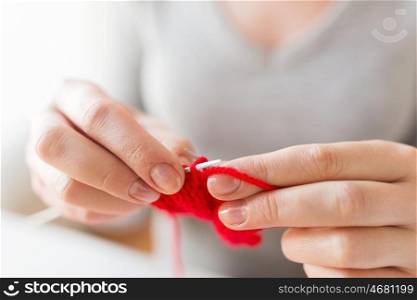 people and needlework concept - close up of woman hands knitting with needles and red yarn. close up of hands knitting with needles and yarn