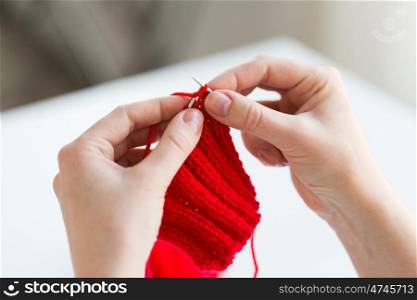 people and needlework concept - close up of woman hands knitting with needles and red yarn. close up of hands knitting with needles and yarn