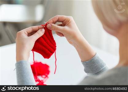 people and needlework concept - woman hands knitting with needles and red yarn. woman hands knitting with needles and yarn