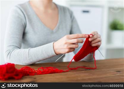 people and needlework concept - woman hands knitting with needles and red yarn. woman hands knitting with needles and yarn