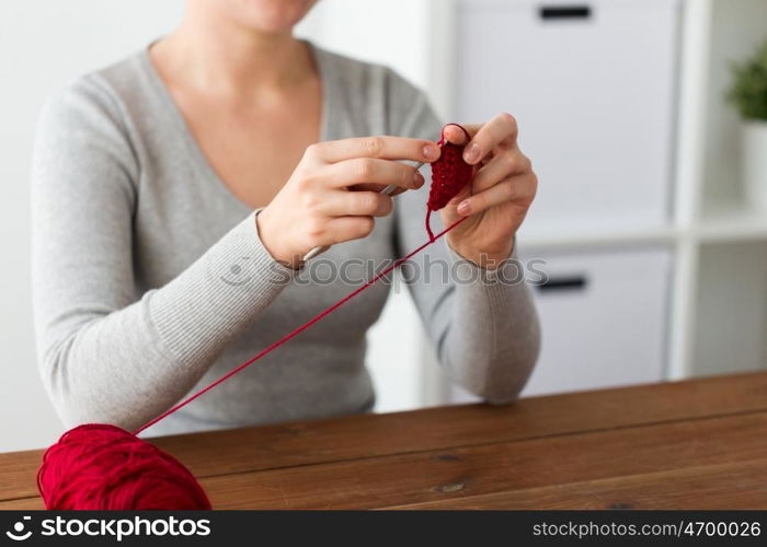 people and needlework concept - woman knitting with crochet hook and red yarn. woman knitting with crochet hook and red yarn