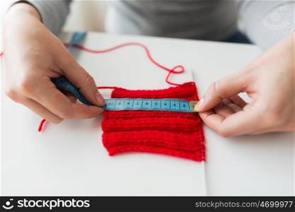 people and needlework concept - woman with measuring tape and knitting on needle. woman with knitting on needle and measuring tape