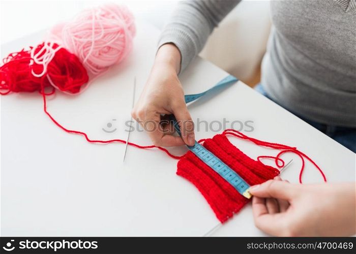 people and needlework concept - woman with measuring tape, knitting, needles and yarn