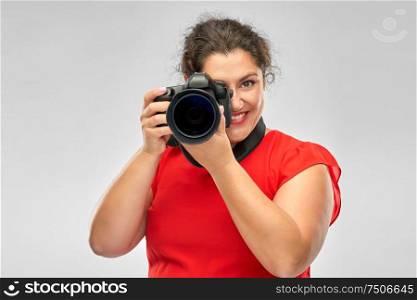 people and photography concept - happy woman photographer in red dress with digital camera over grey background. happy woman photographer with digital camera