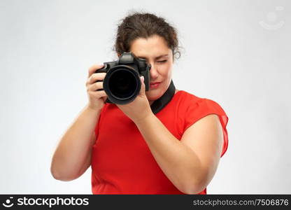 people and photography concept - happy woman photographer in red dress with digital camera over grey background. happy woman photographer with digital camera