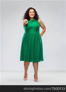 people and portrait concept - happy woman in green dress pointing finger to camera over grey background. woman in green dress pointing finger to camera