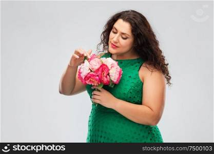people and portrait concept - happy woman in green dress with flower bunch over grey background. happy woman in green dress with flower bunch