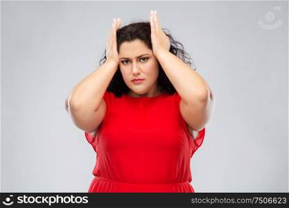 people and portrait concept - woman in red dress suffering from headache over grey background. woman in red dress suffering from headache
