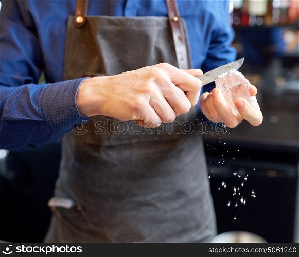 people and profession concept - bartender grinding ice cube with knife at bar. bartender grinding ice cube with knife at bar