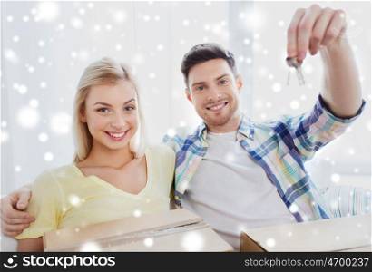people and real estate concept - happy couple with key and boxes moving to new home over snow. happy couple with key and boxes moving to new home